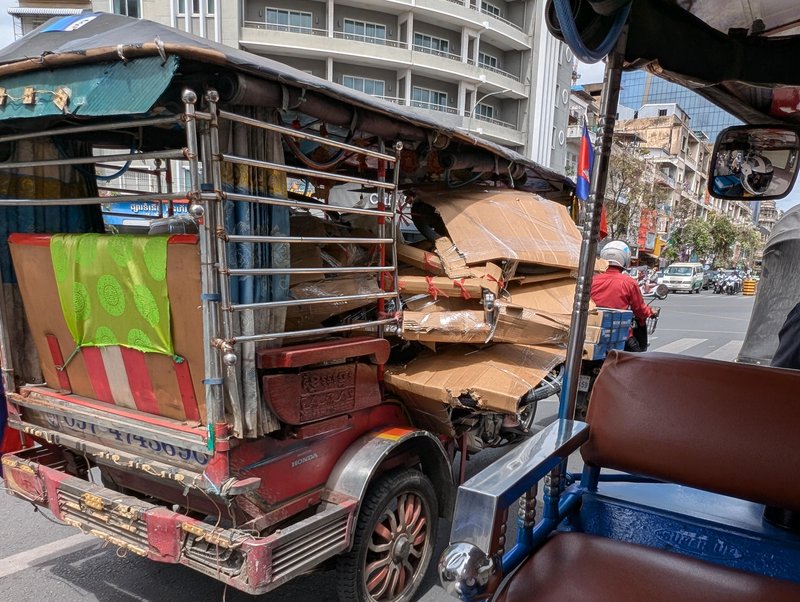 A three wheel vehicle carrying bicycles packed in cardboard
